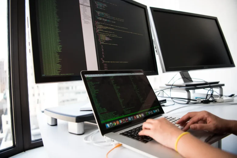 Two engineers comparing cloud AI platform dashboards across AWS, Google and Microsoft consoles on side-by-side monitors